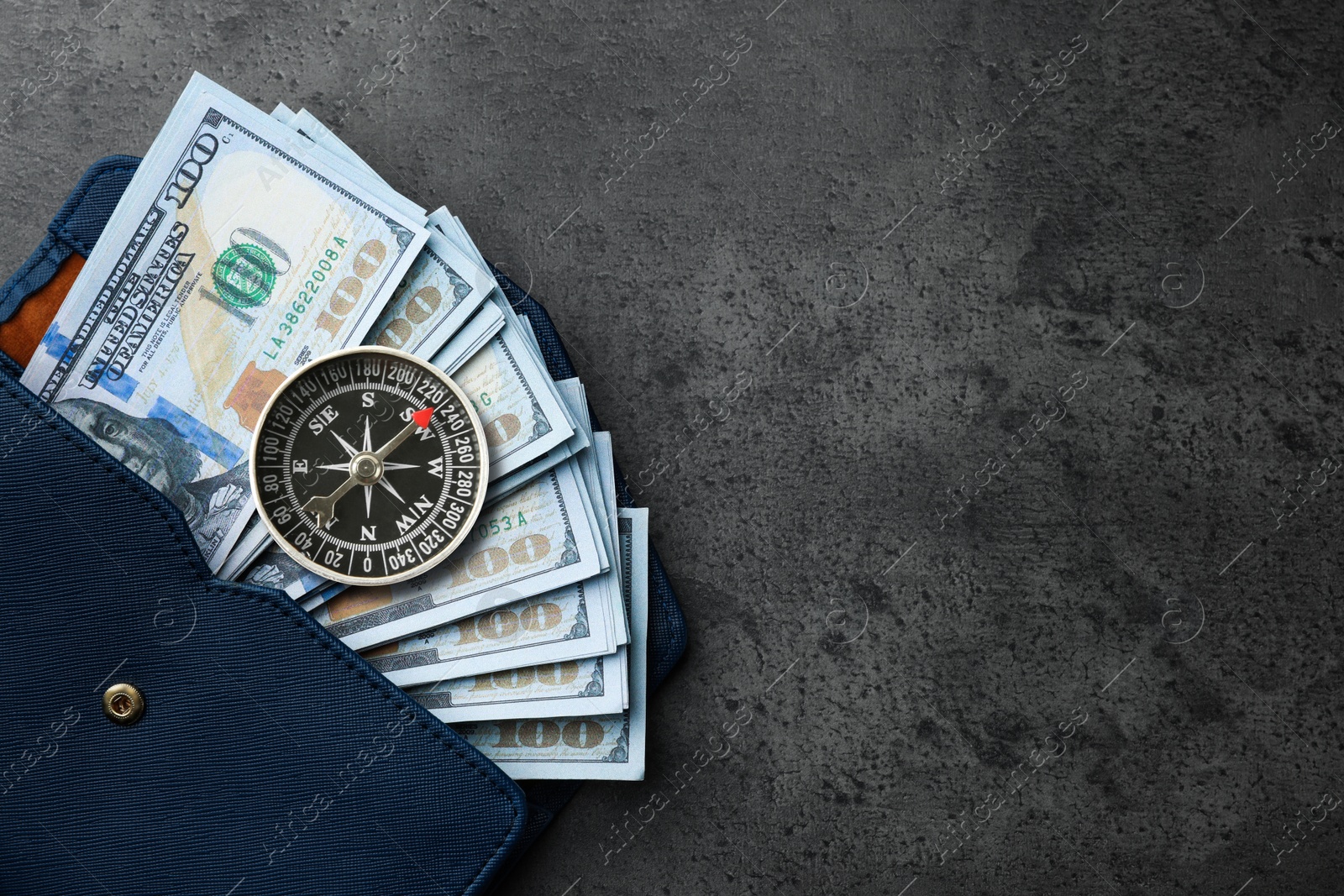 Image of Exchange rate. Wallet with money (dollar banknotes) and compass on dark grey textured background, top view. Space for text