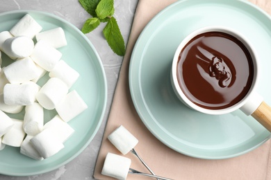 Photo of Fondue pot with dark chocolate and marshmallows on table, flat lay