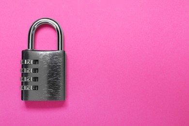 Photo of One steel combination padlock on pink background, top view. Space for text