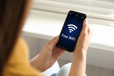 Image of Woman using mobile phone connected to WiFi indoors, closeup