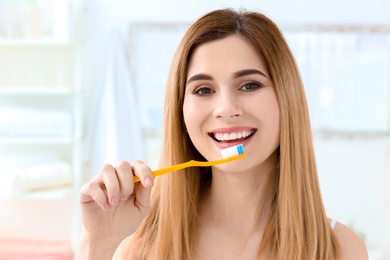 Young woman brushing her teeth indoors