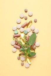 Photo of Different pills and herbs on light yellow background, flat lay. Dietary supplements