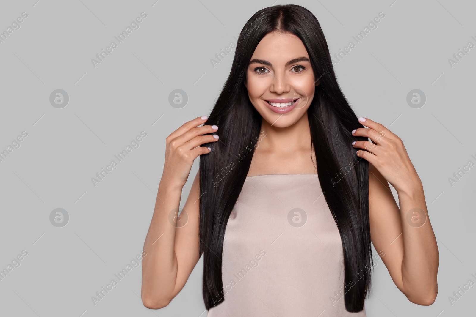 Photo of Portrait of beautiful young woman with healthy strong hair on light grey background. Space for text