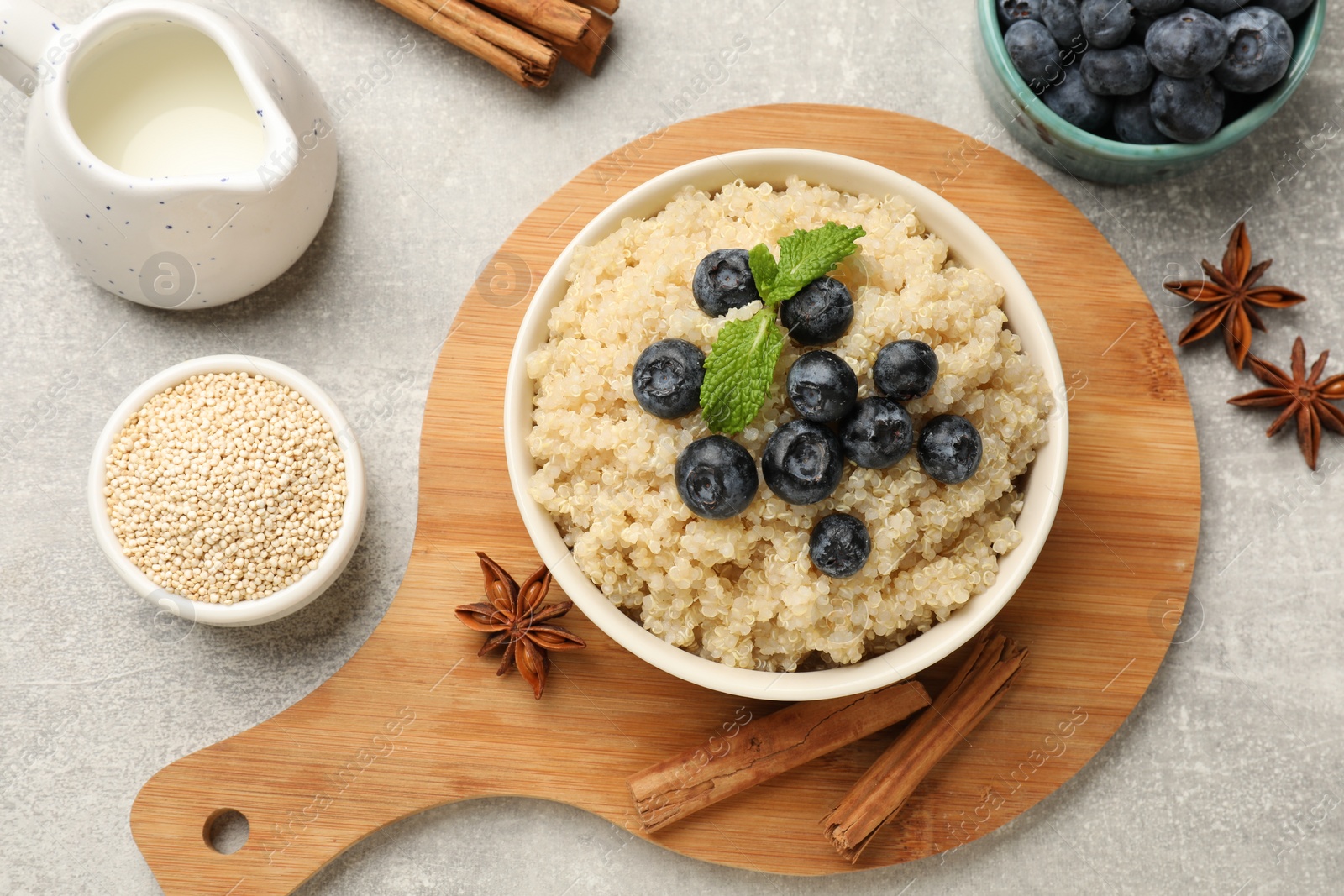 Photo of Flat lay composition with bowl of tasty quinoa porridge and blueberries on light grey table