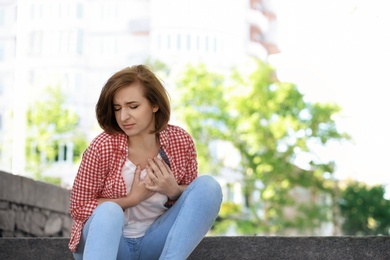 Photo of Mature woman having heart attack, outdoors