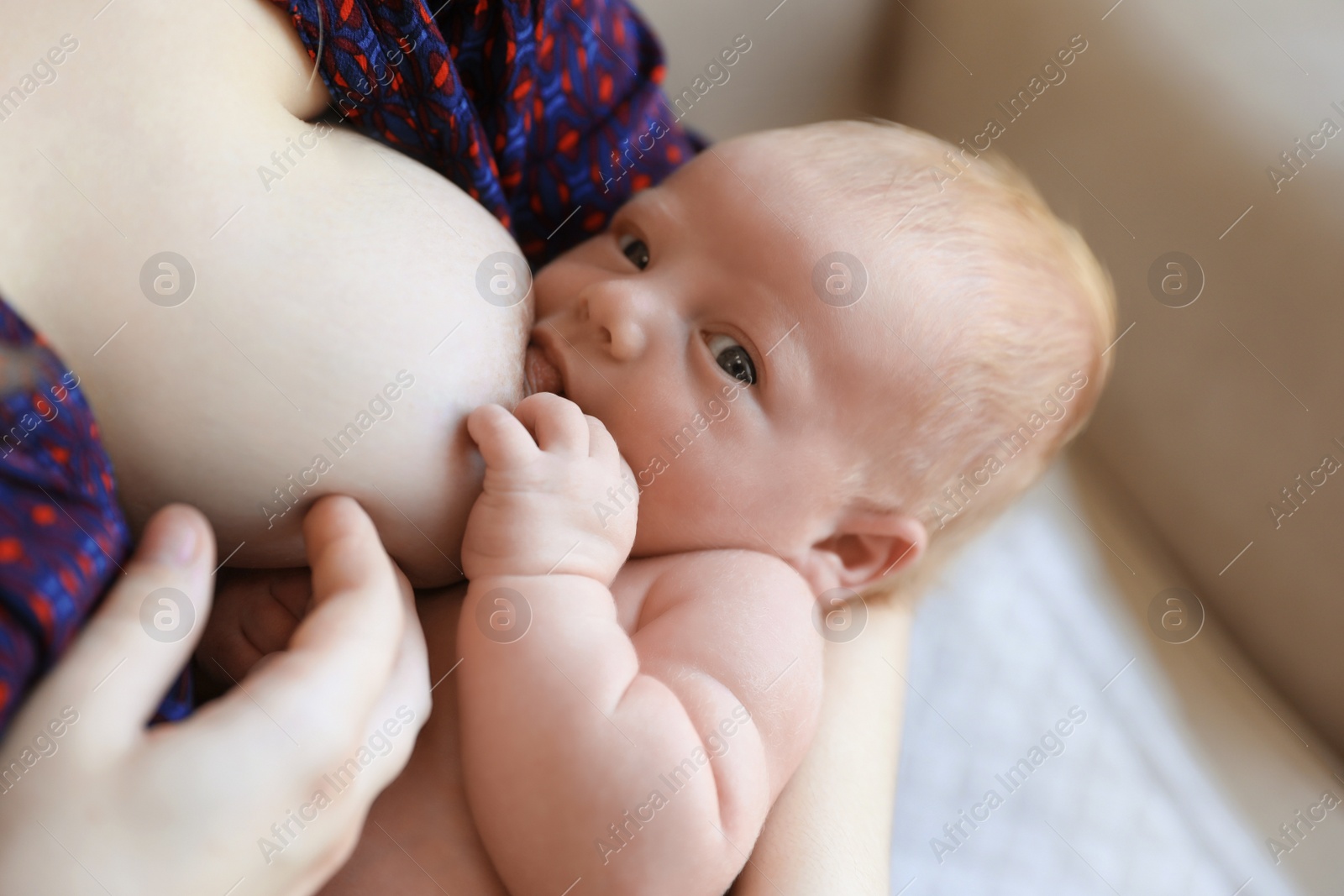 Photo of Woman breast feeding her little baby at home, closeup