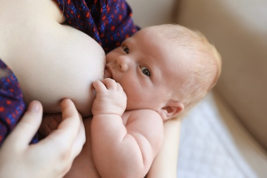 Photo of Woman breast feeding her little baby at home, closeup