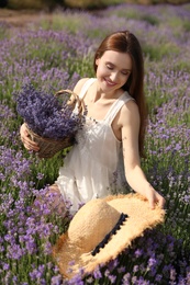 Photo of Young woman with straw hat and wicker basket full of lavender flowers in field