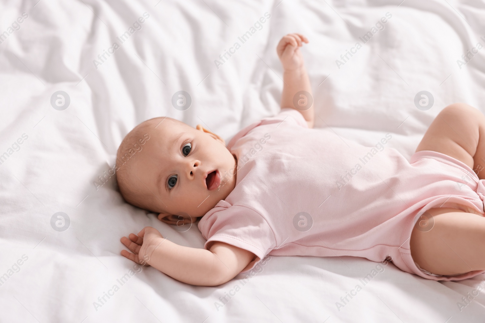 Photo of Cute little baby lying on white sheets