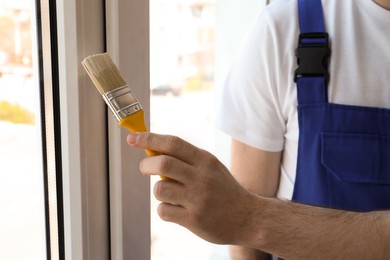 Man painting window frame at home, closeup