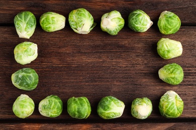 Photo of Frame made with Brussels sprouts on brown wooden table, flat lay. Space for text
