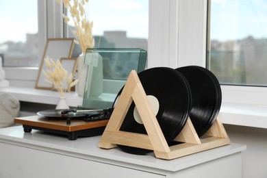 Vinyl records and player on white wooden drawer dresser indoors