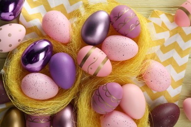 Photo of Decorative nests with many beautiful Easter eggs on table, flat lay
