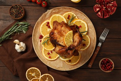 Photo of Baked chicken with orange slices and ingredients on wooden table, flat lay