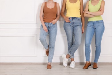 Photo of Women in stylish jeans near white wall indoors, closeup