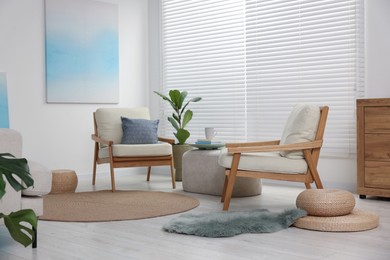 Photo of Comfortable beige armchairs, ottoman and houseplant in living room. Interior design