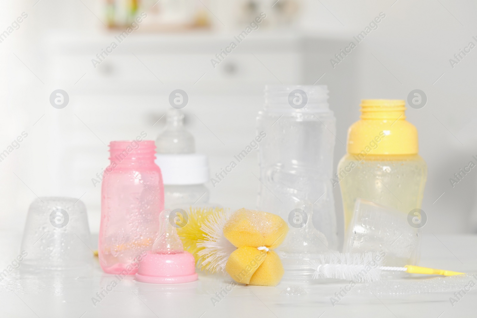 Photo of Clean baby bottles with nipples after sterilization and cleaning tools on white table indoors