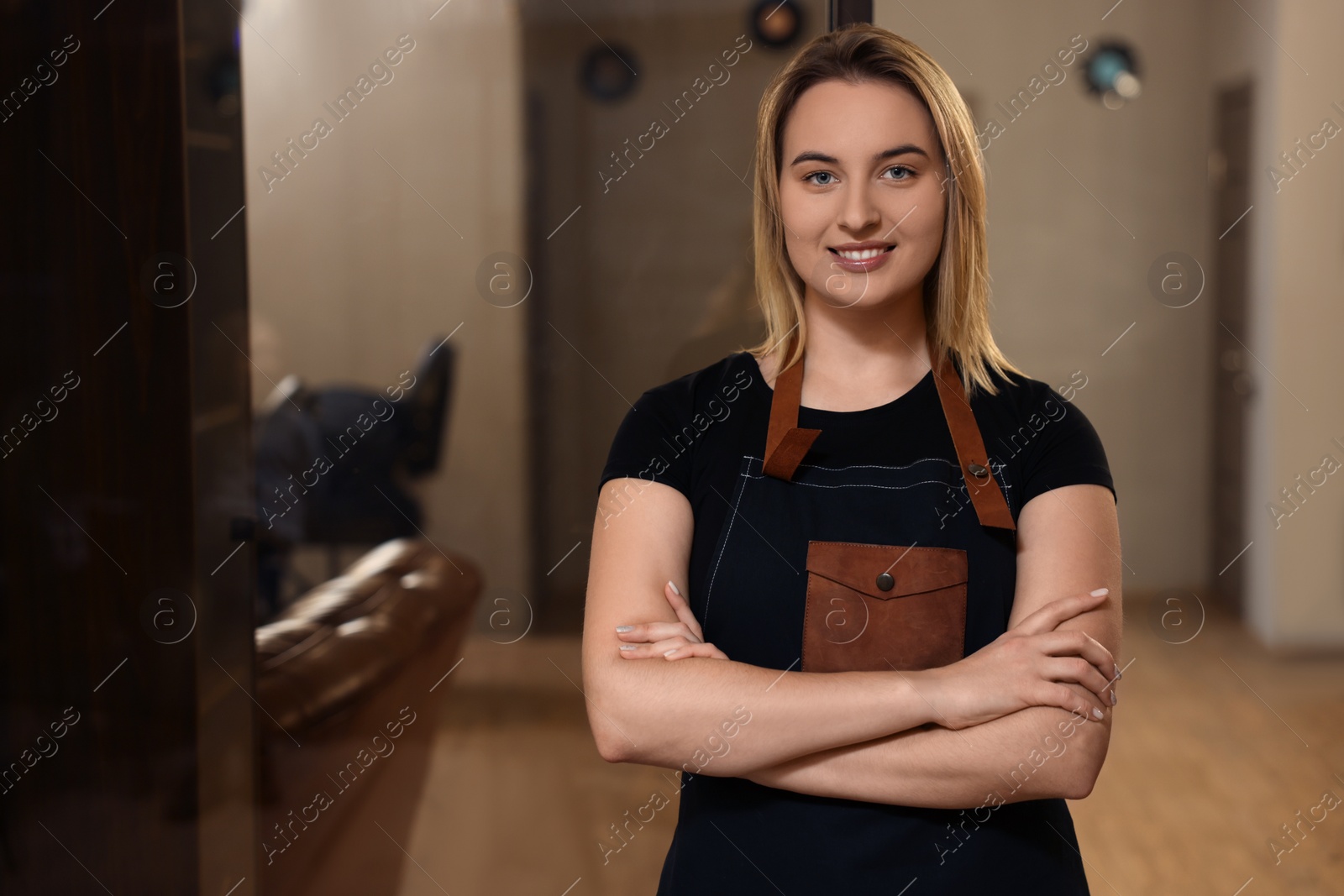 Photo of Portrait of professional hairdresser wearing apron in beauty salon, space for text