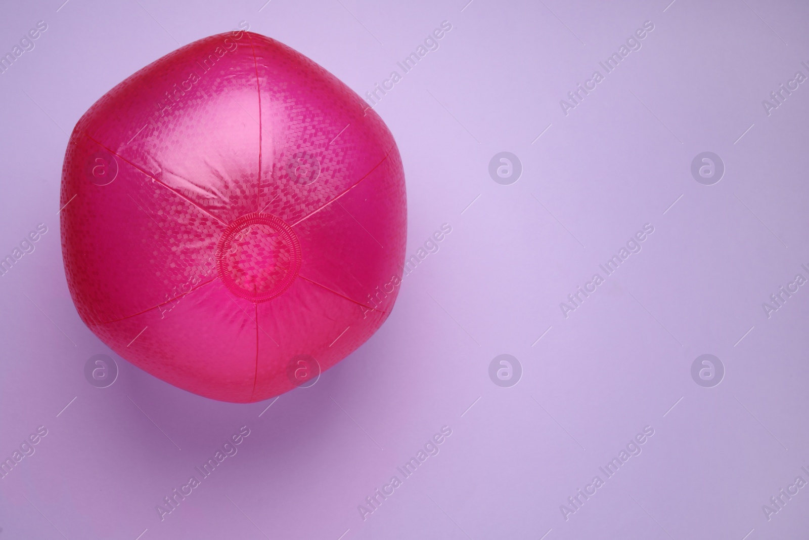 Photo of Bright beach ball on violet background, top view. Space for text