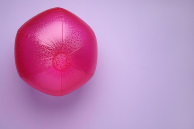 Photo of Bright beach ball on violet background, top view. Space for text