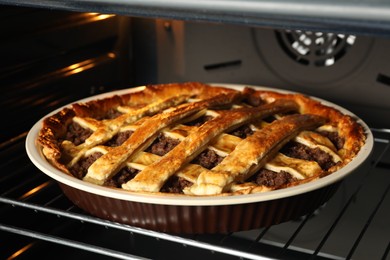 Delicious meat pie in oven, closeup view