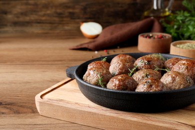 Photo of Tasty cooked meatballs served on wooden table. Space for text