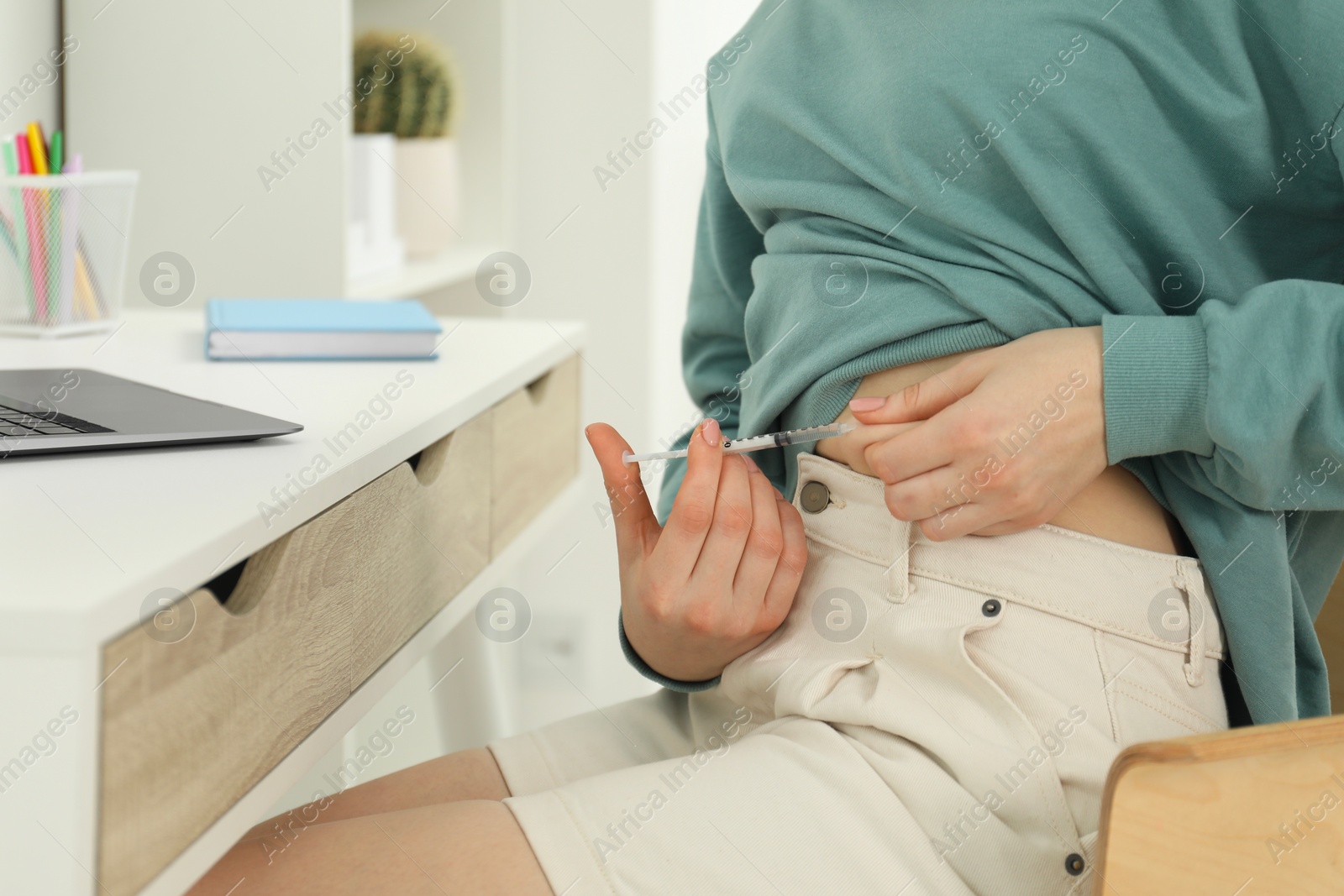 Photo of Diabetes. Woman making insulin injection into her belly at table indoors, closeup