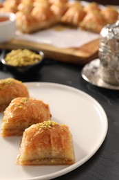 Photo of Delicious sweet baklava with pistachios on black table, closeup