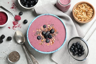 Delicious acai smoothie with granola and chia seeds served on grey table, flat lay