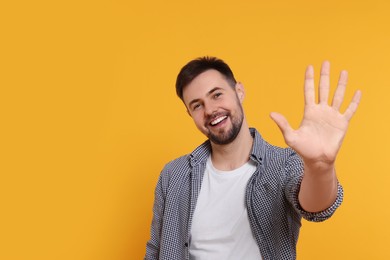 Photo of Man giving high five on yellow background. Space for text