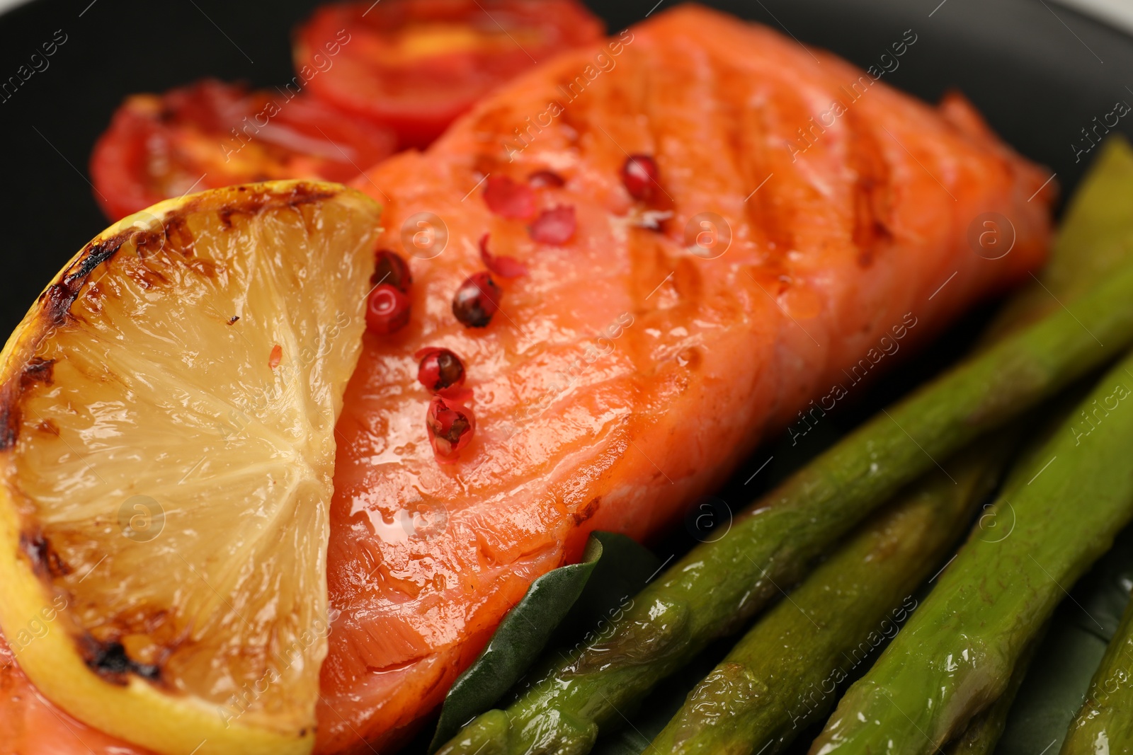 Photo of Tasty grilled salmon, lemon and asparagus, closeup