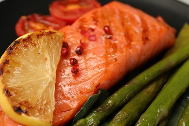 Photo of Tasty grilled salmon, lemon and asparagus, closeup