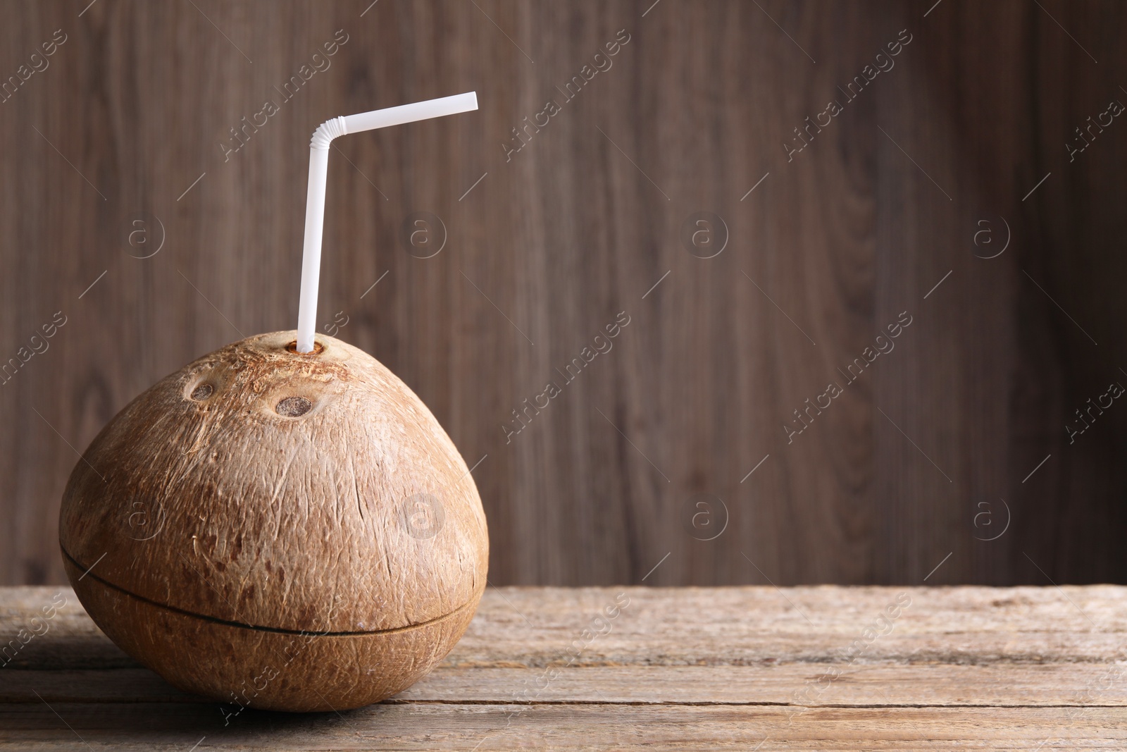 Photo of Coconut water. Fresh nut with straw on wooden table, space for text