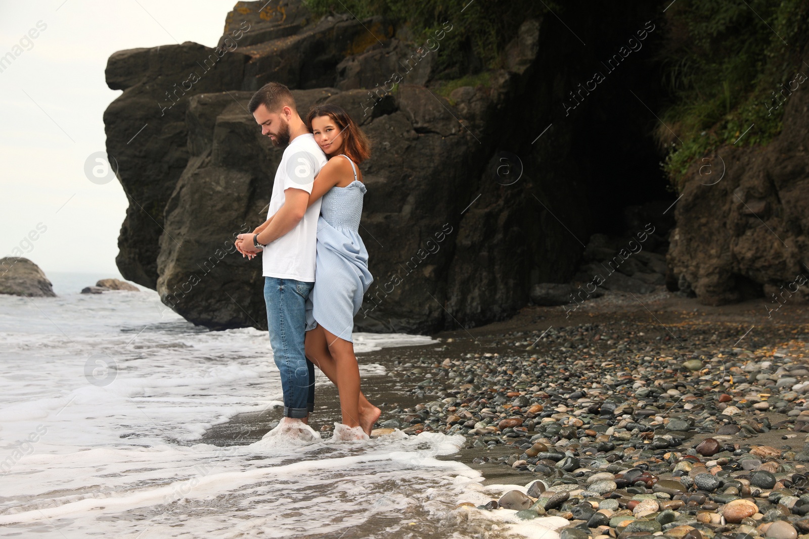 Photo of Happy young couple on beach near sea. Space for text