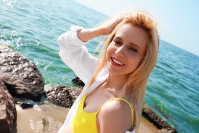 Photo of Beautiful young woman near sea on sunny day in summer