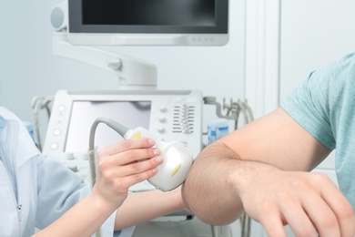 Photo of Doctor conducting ultrasound examination of patient's elbow in clinic, closeup