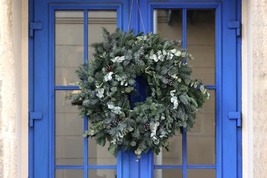 Photo of Beautiful Christmas wreath hanging on blue glass door