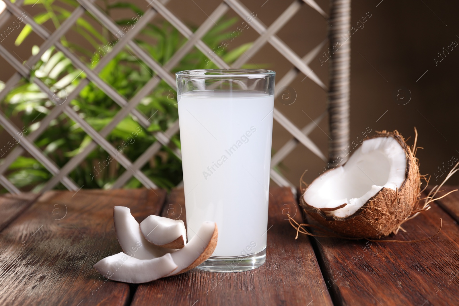 Photo of Glass of coconut water, leaf and nuts on wooden table