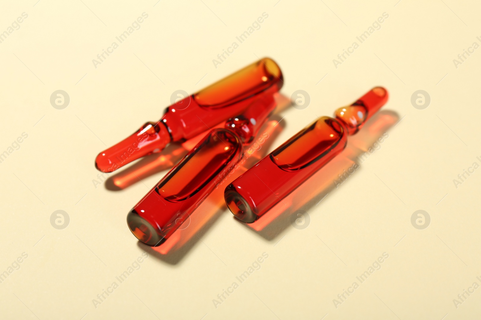 Photo of Glass ampoules with liquid on beige background