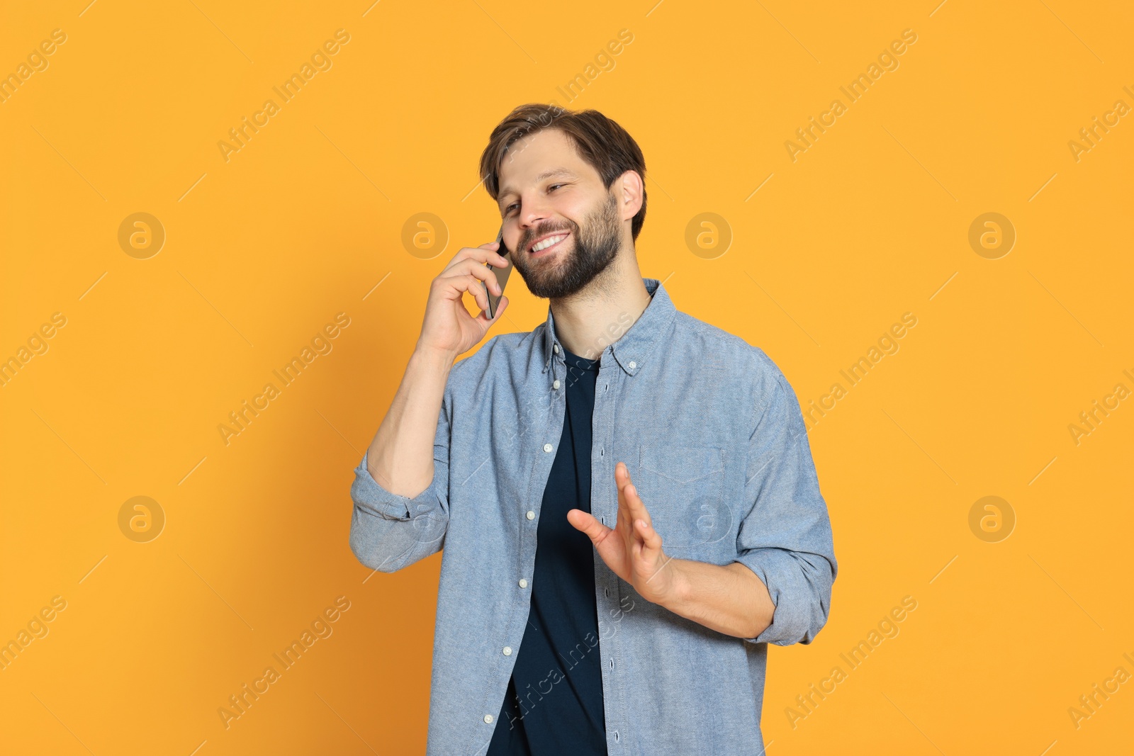 Photo of Man talking on smartphone against orange background