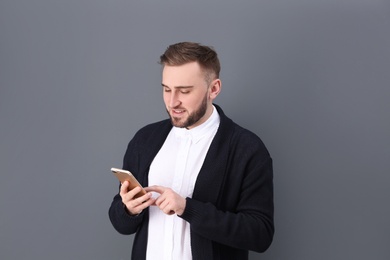 Photo of Portrait of confident young man with mobile phone on color background