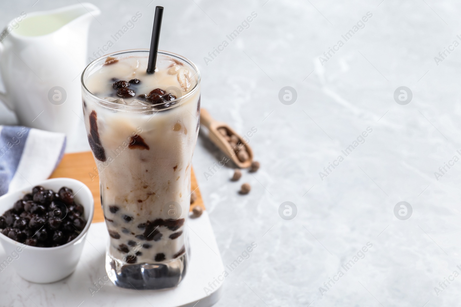 Photo of Bubble milk tea with tapioca balls on light grey table. Space for text