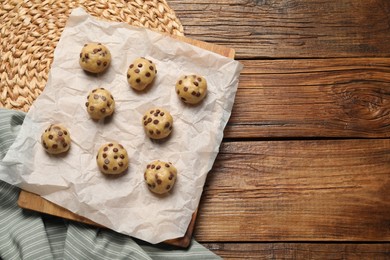 Photo of Uncooked chocolate chip cookies on wooden table, top view. Space for text