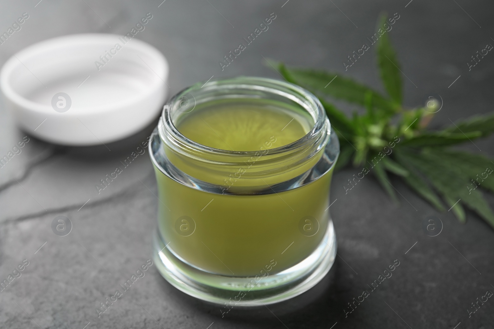 Photo of Jar of hemp cream on dark stone table, closeup. Organic cosmetics