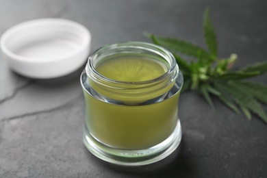 Photo of Jar of hemp cream on dark stone table, closeup. Organic cosmetics