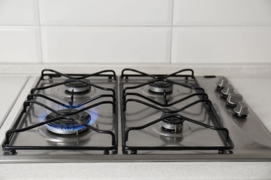 Photo of Gas cooktop with burning blue flame in kitchen