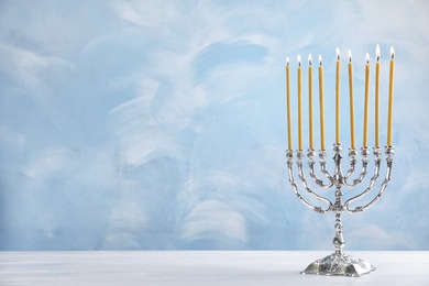 Photo of Hanukkah menorah on table against color background