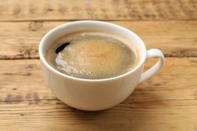 Cup of aromatic coffee on wooden table, closeup