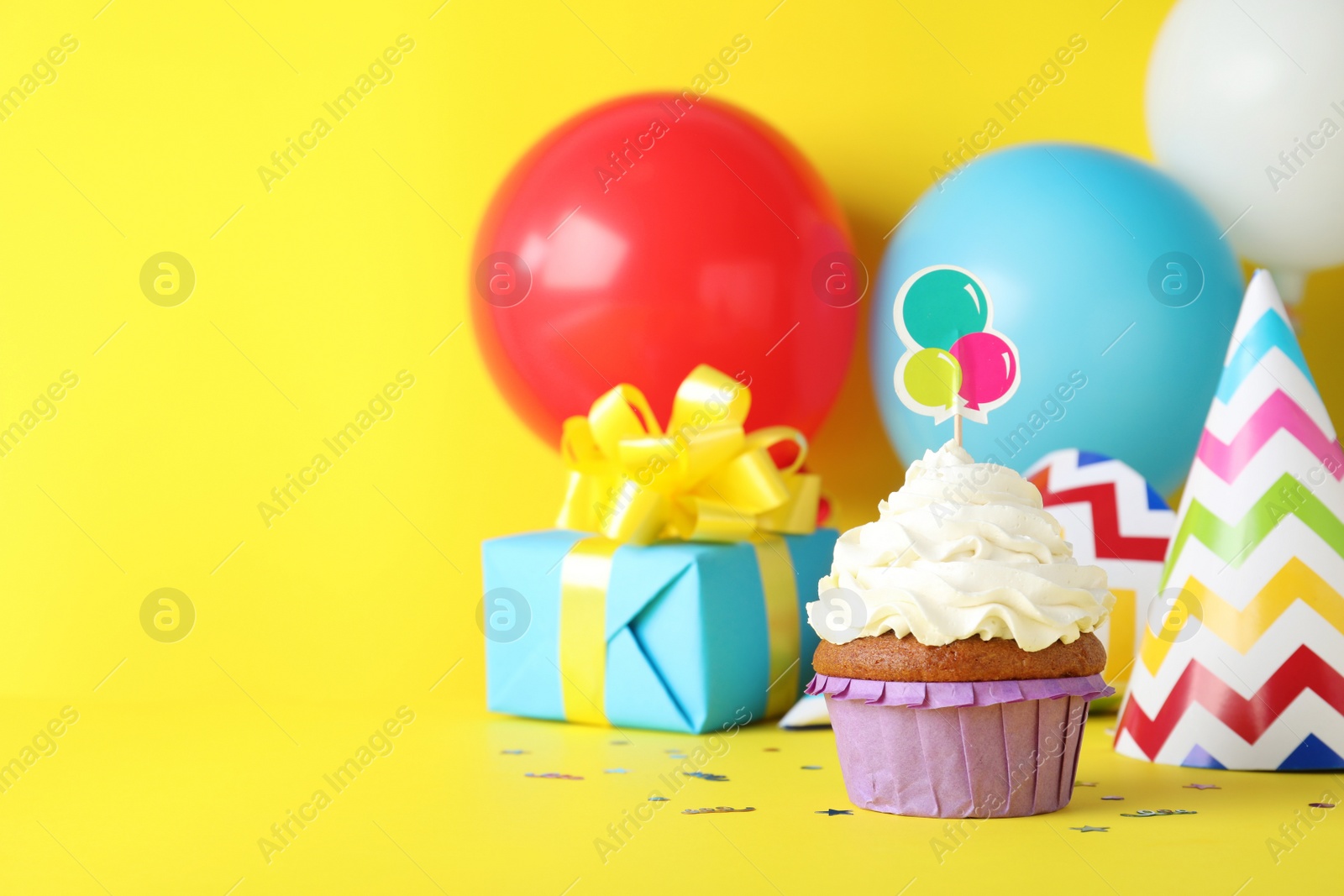 Photo of Delicious birthday cupcake on yellow background, space for text