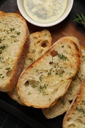 Tasty baguette with garlic, dill and oil on table, top view